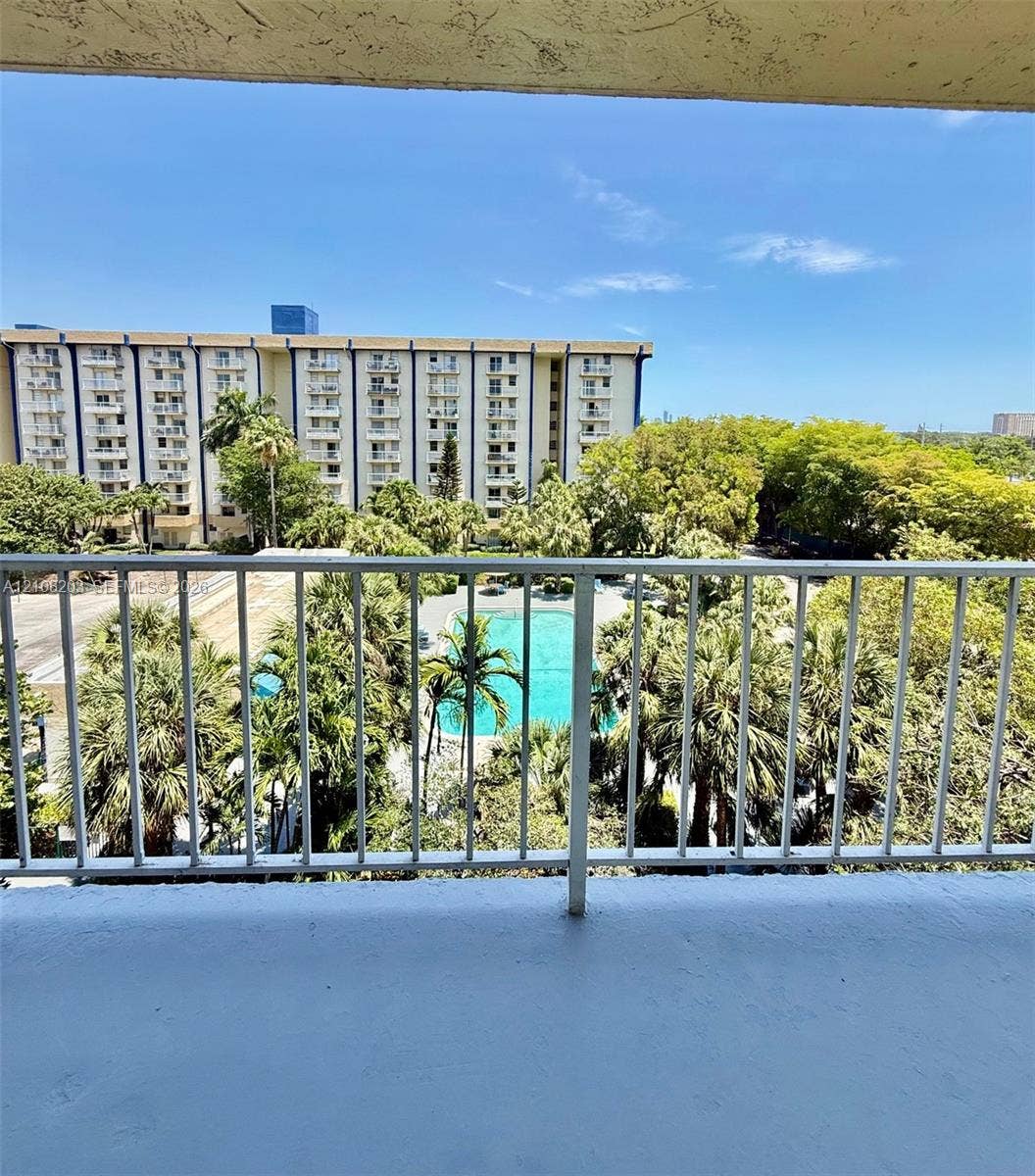 801 NW 47th Avenue, #619W, Miami, Miami, FL 33126 Open-air balcony featuring white metal railings, overlooking an outdoor swimming pool, paved hardscaping, and mature palm trees