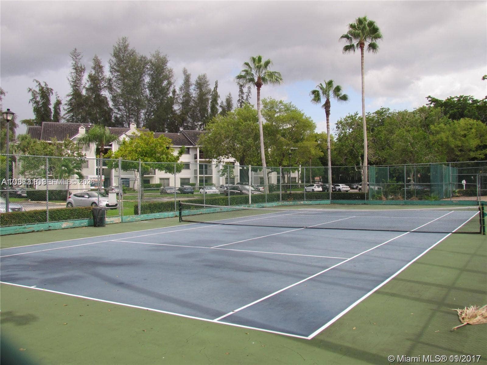 Coral Springs, Coral Springs, FL 33071 Tennis court with a fenced perimeter and surrounding mature palm trees