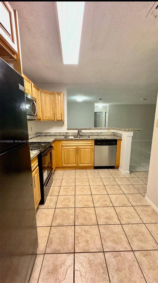 Coral Springs, Coral Springs, FL 33071 Kitchen featuring light wood cabinetry, stone-finish countertops, stainless steel dishwasher, integrated range and microwave, and ceramic tile flooring