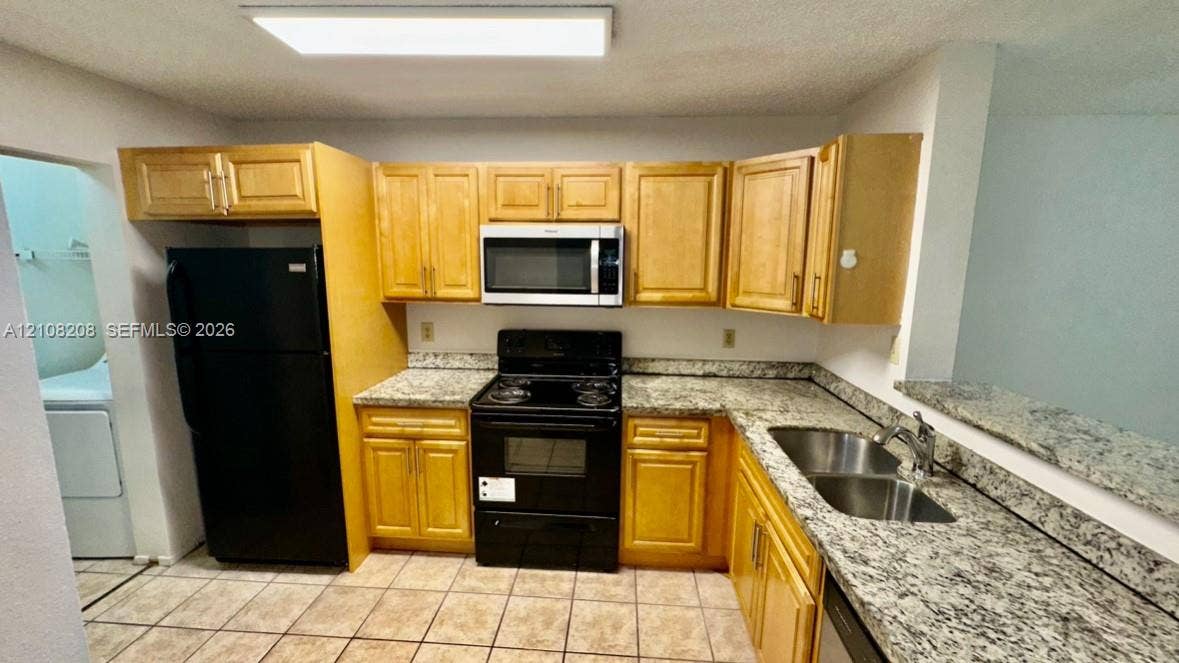 Coral Springs, Coral Springs, FL 33071 Kitchen featuring light-finish cabinetry, stone-patterned countertops, a stainless steel double-basin sink, a built-in microwave, and ceramic tile flooring