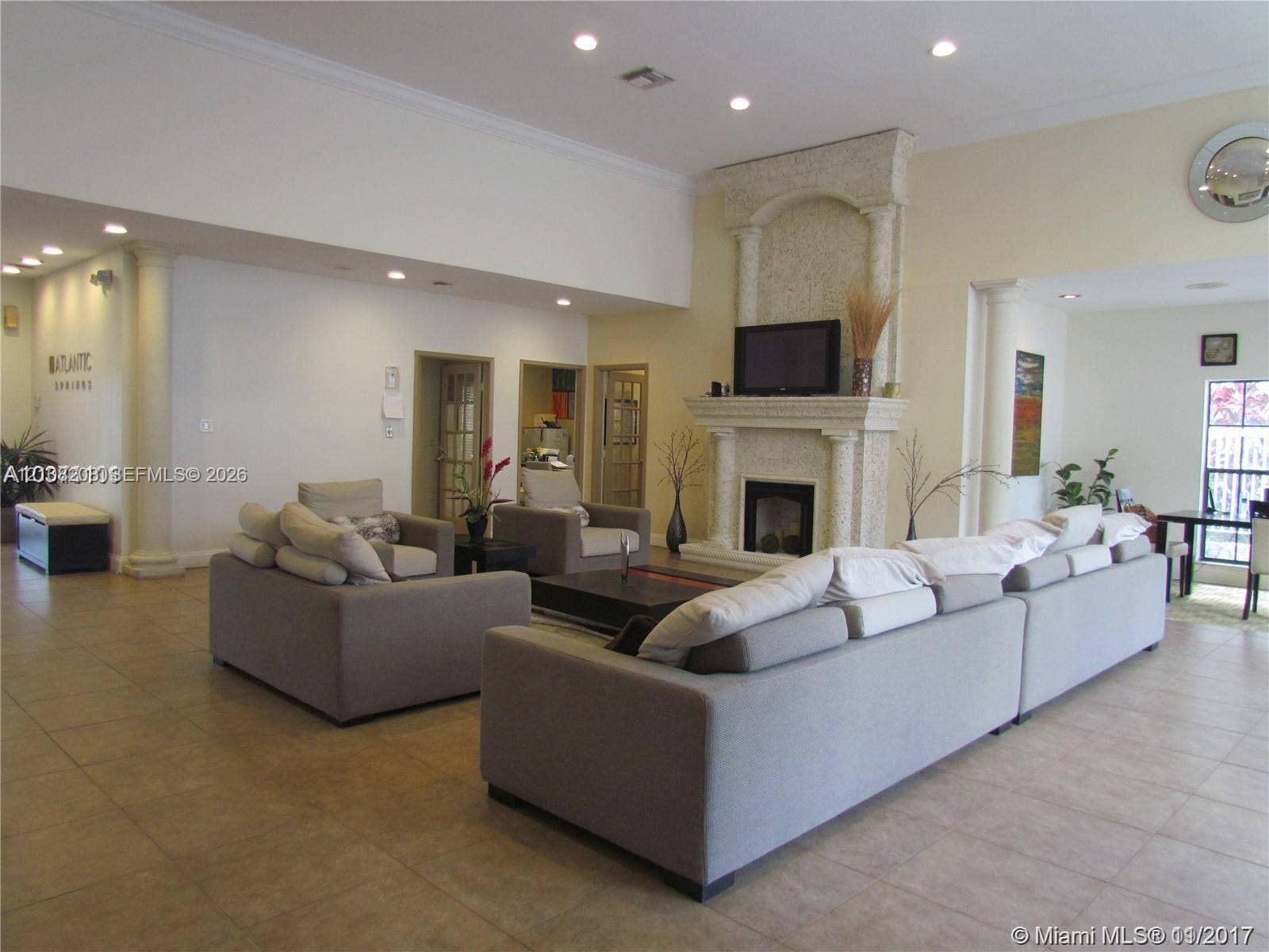 Coral Springs, Coral Springs, FL 33071 Open-concept living space featuring high ceilings, recessed lighting, tile flooring, and a stone-clad fireplace with architectural columns