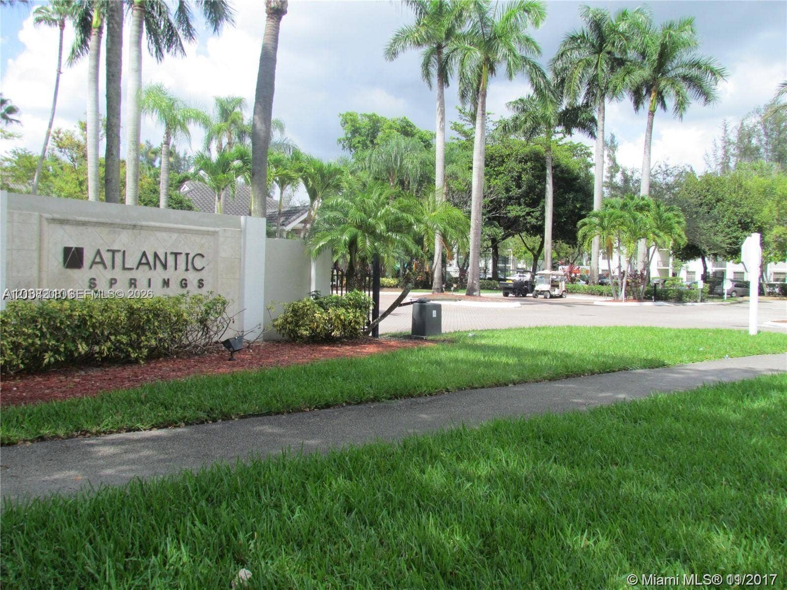 Coral Springs, Coral Springs, FL 33071 Community entrance featuring stone-clad monument signage, manicured turf, mature palms, and paved roadways