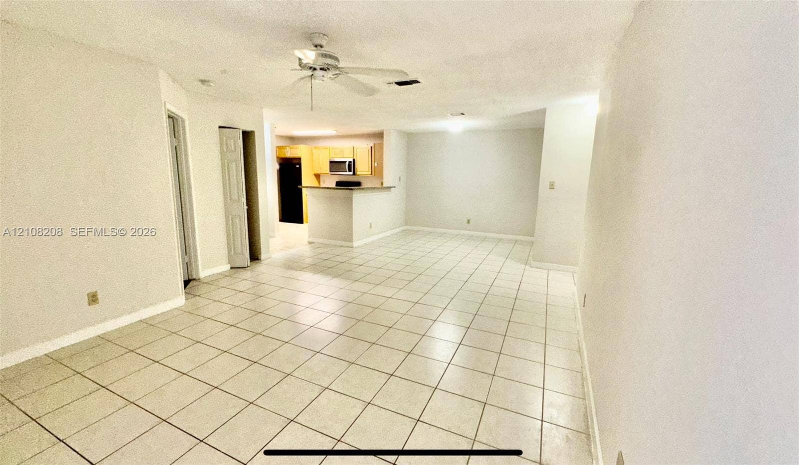 Coral Springs, Coral Springs, FL 33071 Open-concept interior featuring light-colored floor tiling, kitchen peninsula with a countertop overhang, ceiling fan with light fixture, and light-toned cabinetry