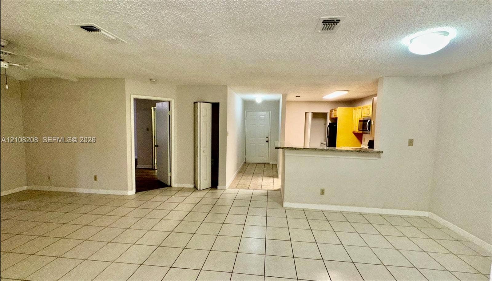 Coral Springs, Coral Springs, FL 33071 Neutral-toned tile flooring, pass-through kitchen counter, ceiling-mounted lighting, and folding closet door