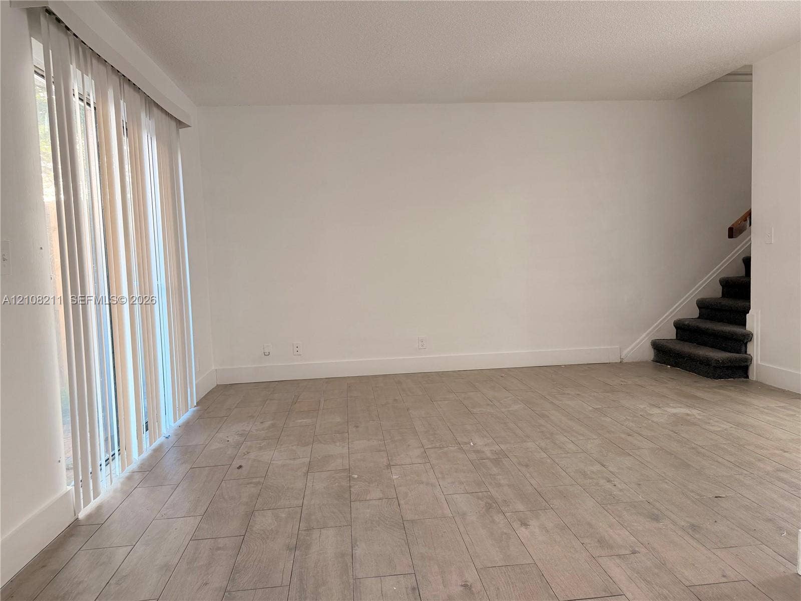 5924 NW 21st Street, #49-A, Lauderhill, Lauderhill, FL 33313 Neutral interior featuring wood-finish tile flooring, vertical window blinds, and a staircase with carpeted treads