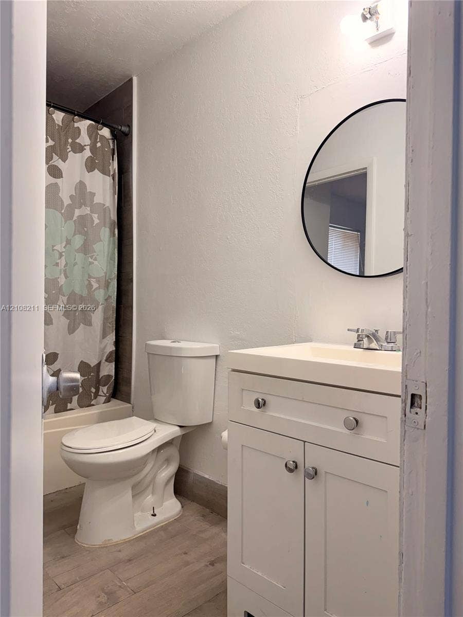 5924 NW 21st Street, #49-A, Lauderhill, Lauderhill, FL 33313 Bathroom featuring a vanity with white cabinetry, a circular wall-mounted mirror, wood-finish flooring, and a shower-tub combination