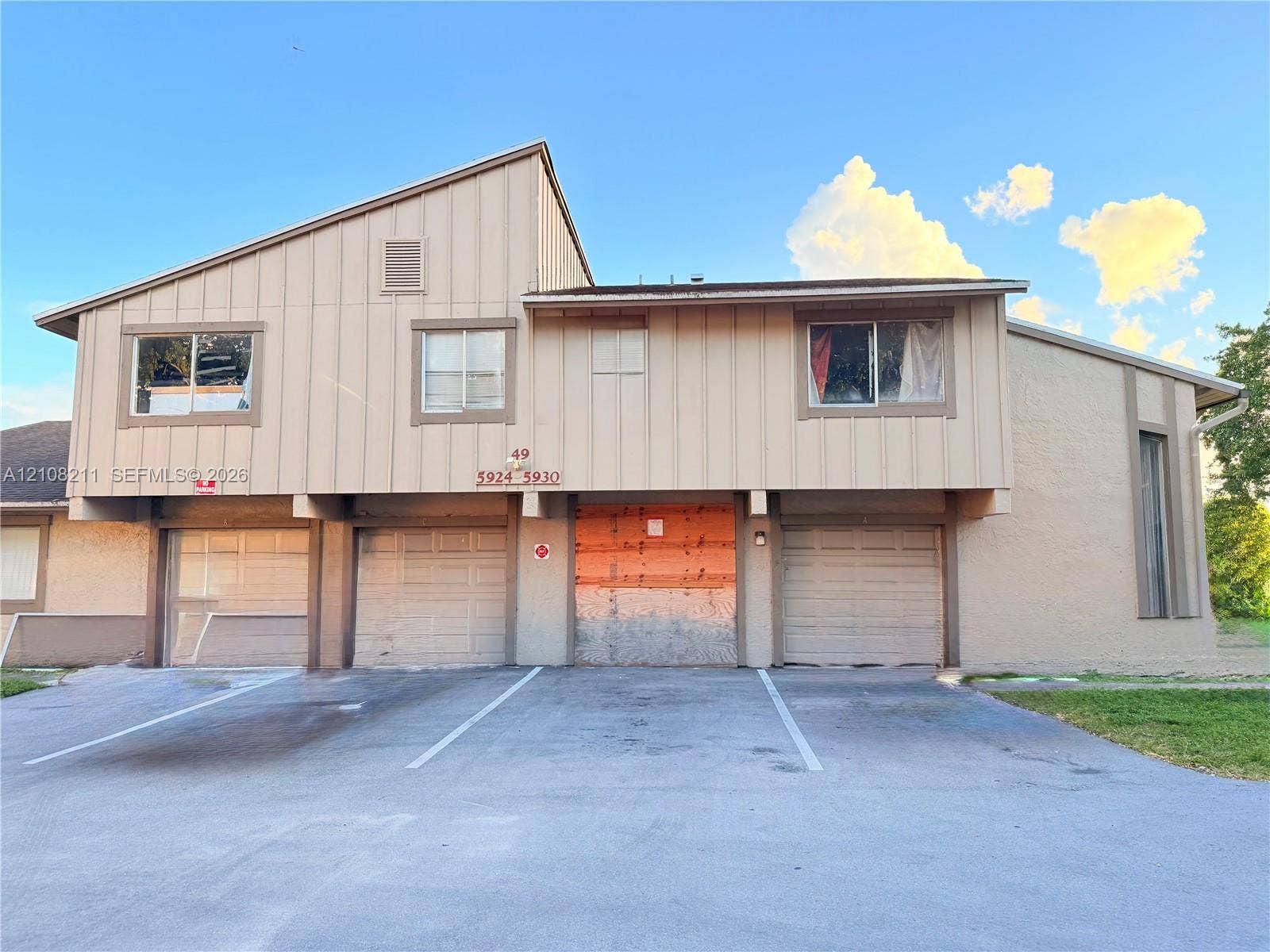 5924 NW 21st Street, #49-A, Lauderhill, Lauderhill, FL 33313 Multi-unit exterior featuring vertical board-and-batten siding, a shed roofline, and three attached garage bays with paneled doors