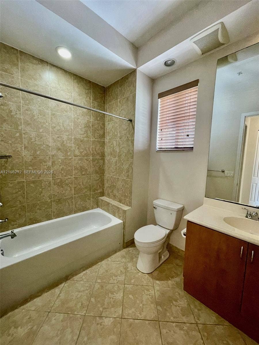 Sunrise, FL 33323 Bathroom featuring a tiled tub-shower surround, vanity with an integrated countertop sink, large wall-mounted mirror, and tile flooring