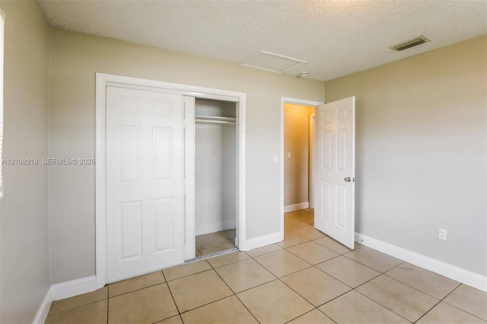 Neutral-toned interior featuring ceramic tile flooring, sliding bypass closet doors, and traditional six-panel interior doors