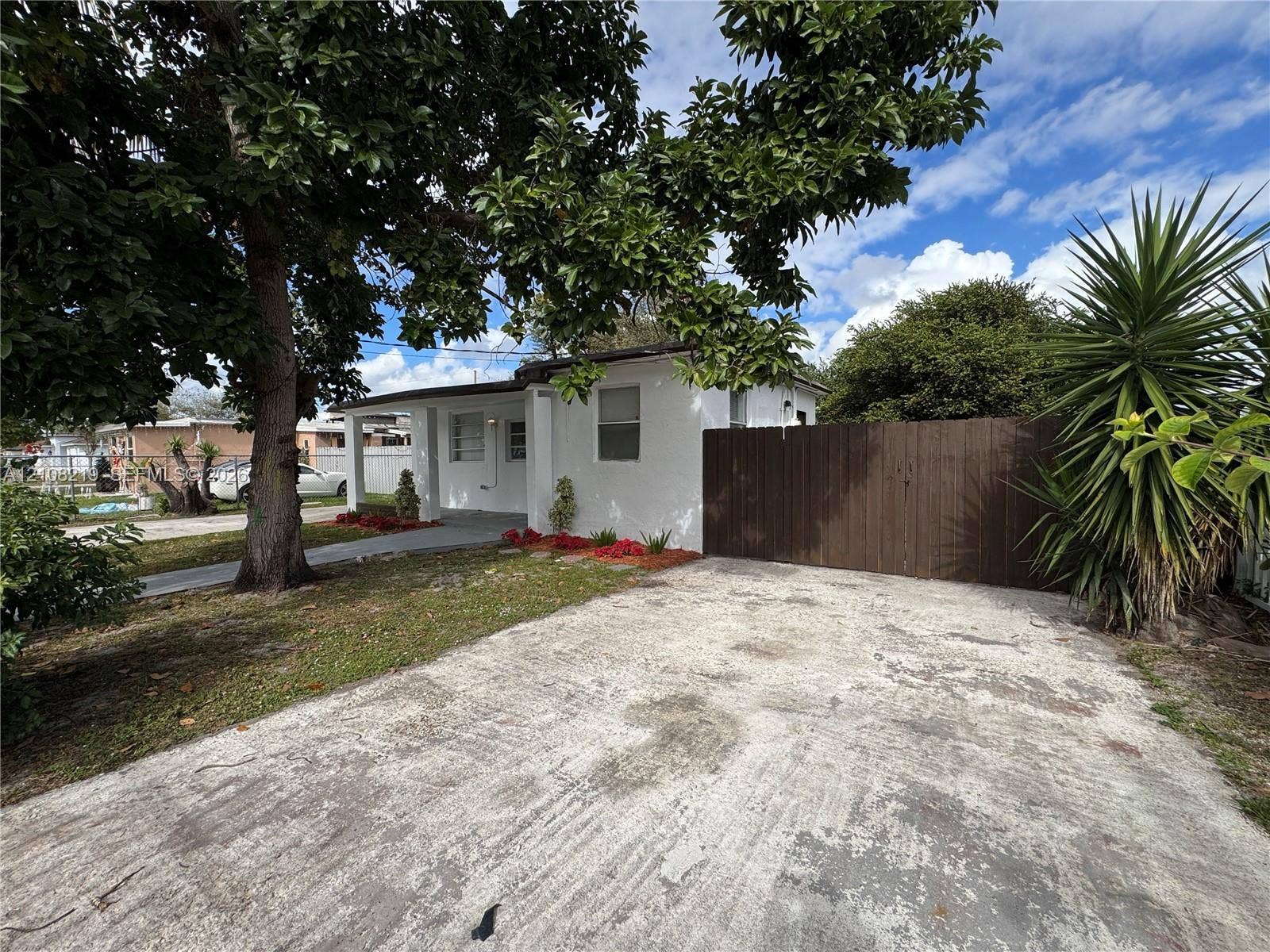 2381 NW 153rd Street, #2353, Miami Gardens, Miami Gardens, FL 33054 Stucco exterior featuring a concrete driveway, covered porch entrance, and wood-panel privacy fencing