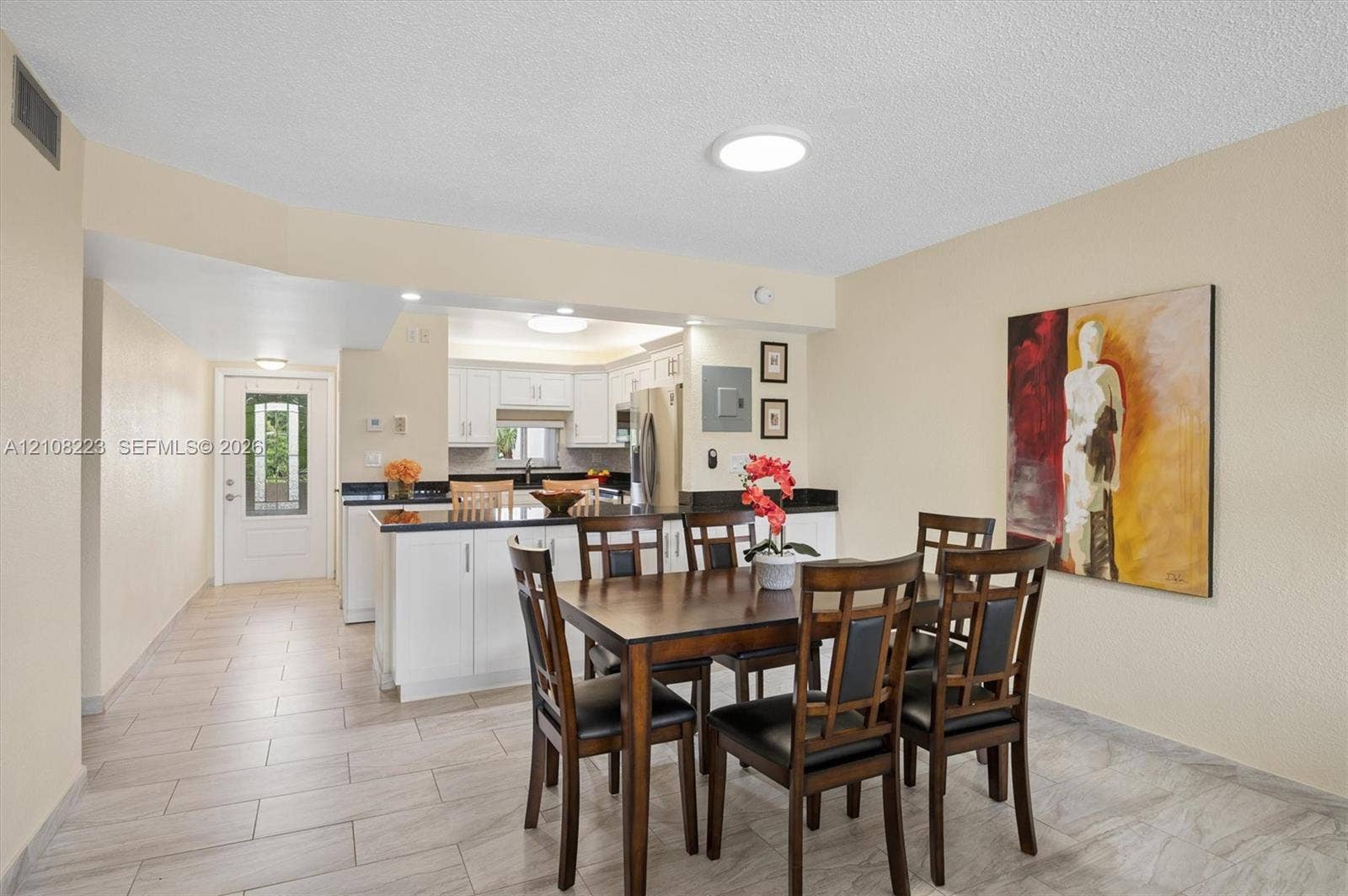 311 S Hollybrook Drive, #309, Pembroke Pines, FL 33025 Kitchen featuring white cabinetry, dark countertops, tile flooring, and a glass-paneled exterior entry door