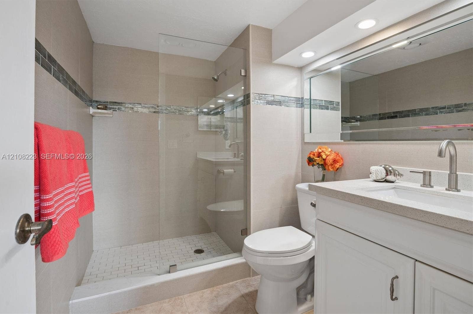 311 S Hollybrook Drive, #309, Pembroke Pines, FL 33025 Bathroom featuring a walk-in glass-enclosed shower, mosaic tile wall accent, white vanity cabinet with a solid surface countertop, and integrated recessed lighting