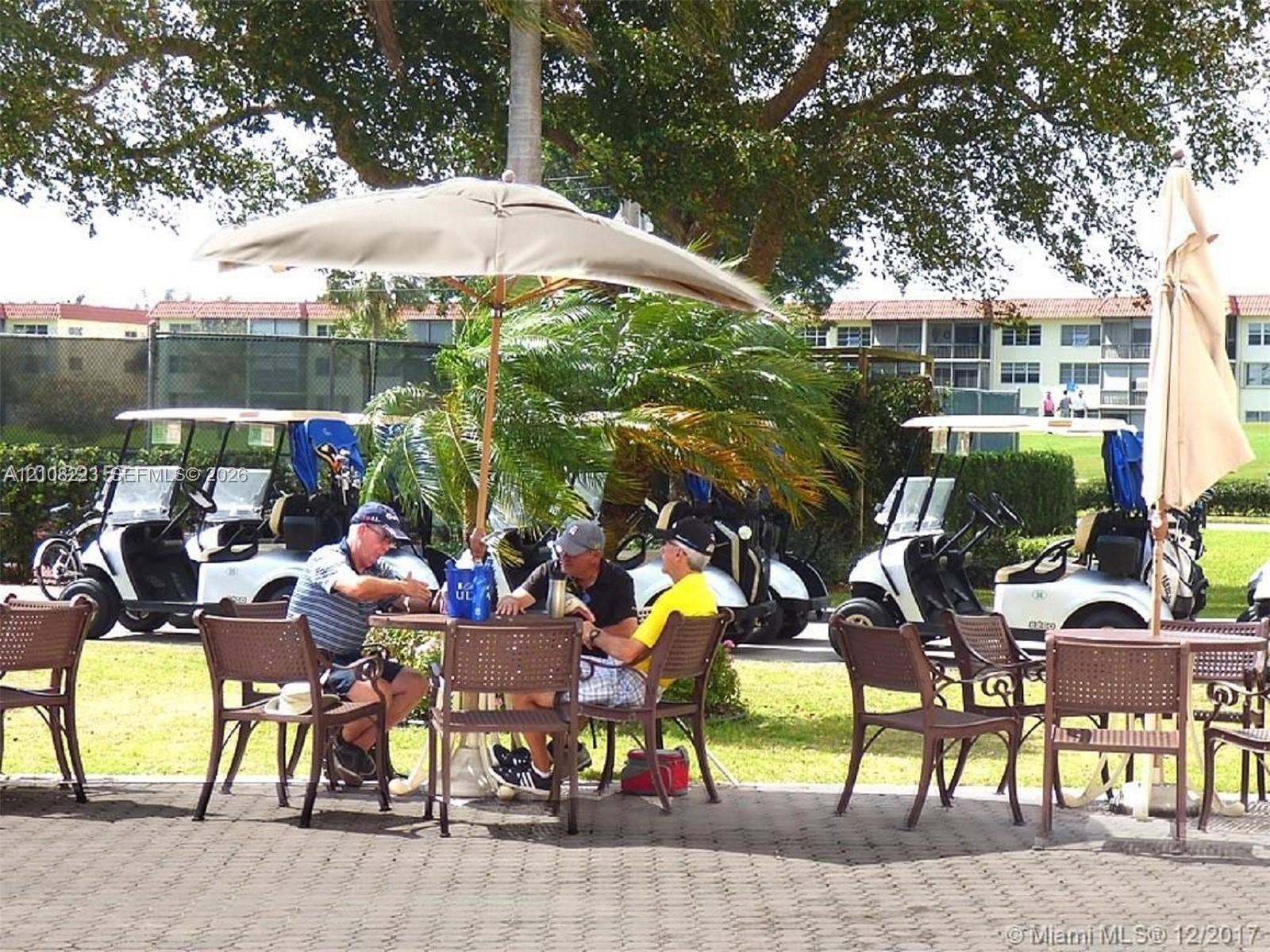 311 S Hollybrook Drive, #309, Pembroke Pines, FL 33025 Paver patio area featuring mature tree canopy, landscaping, and golf course access