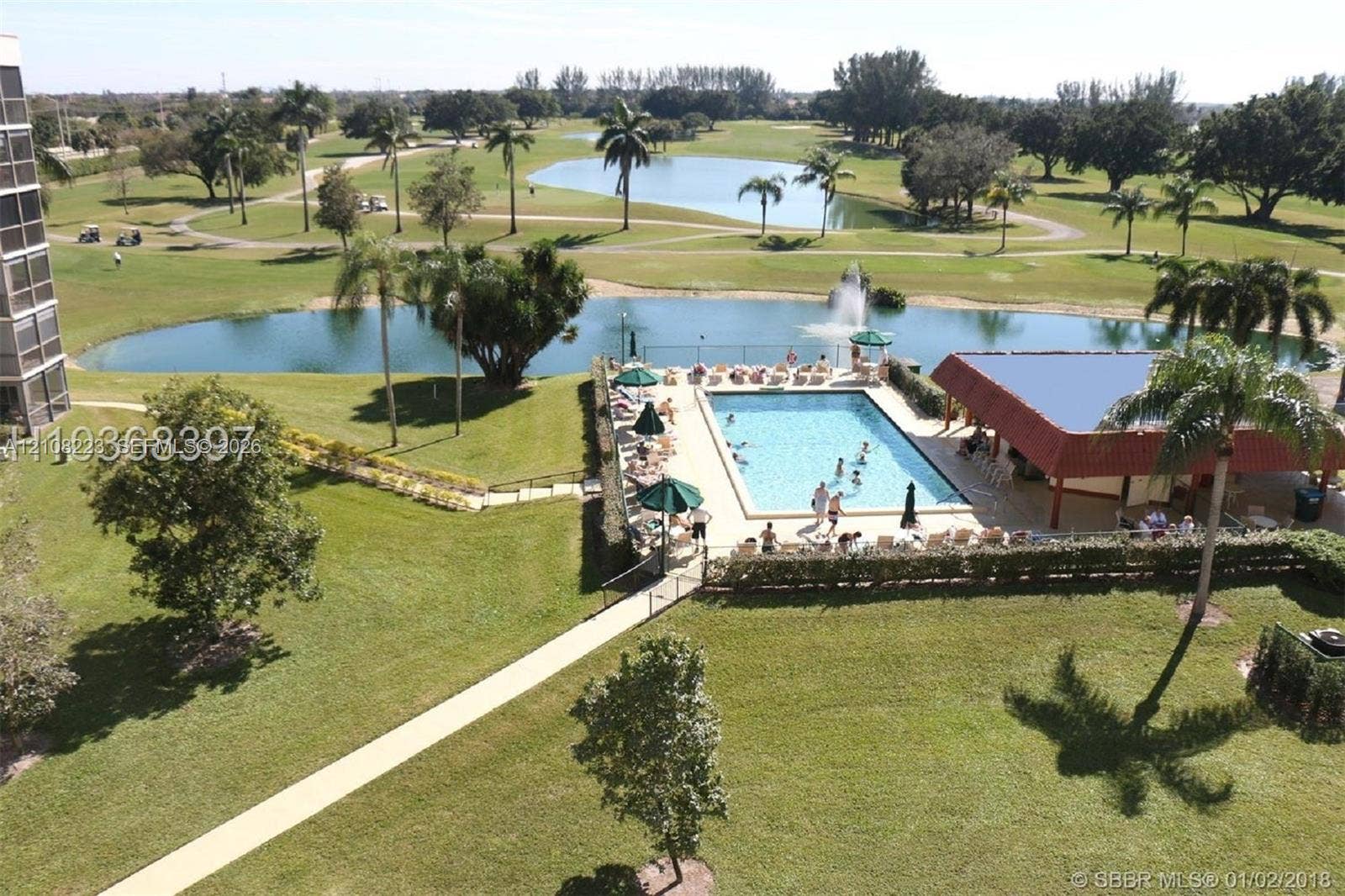 311 S Hollybrook Drive, #309, Pembroke Pines, FL 33025 Community amenities featuring a swimming pool, a covered poolside pavilion, a water feature, and expansive green space bordering a golf course