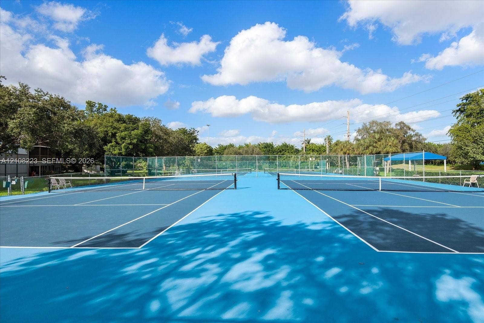 311 S Hollybrook Drive, #309, Pembroke Pines, FL 33025 Dual tennis courts featuring a blue hard-court surface, perimeter fencing, and integrated net systems