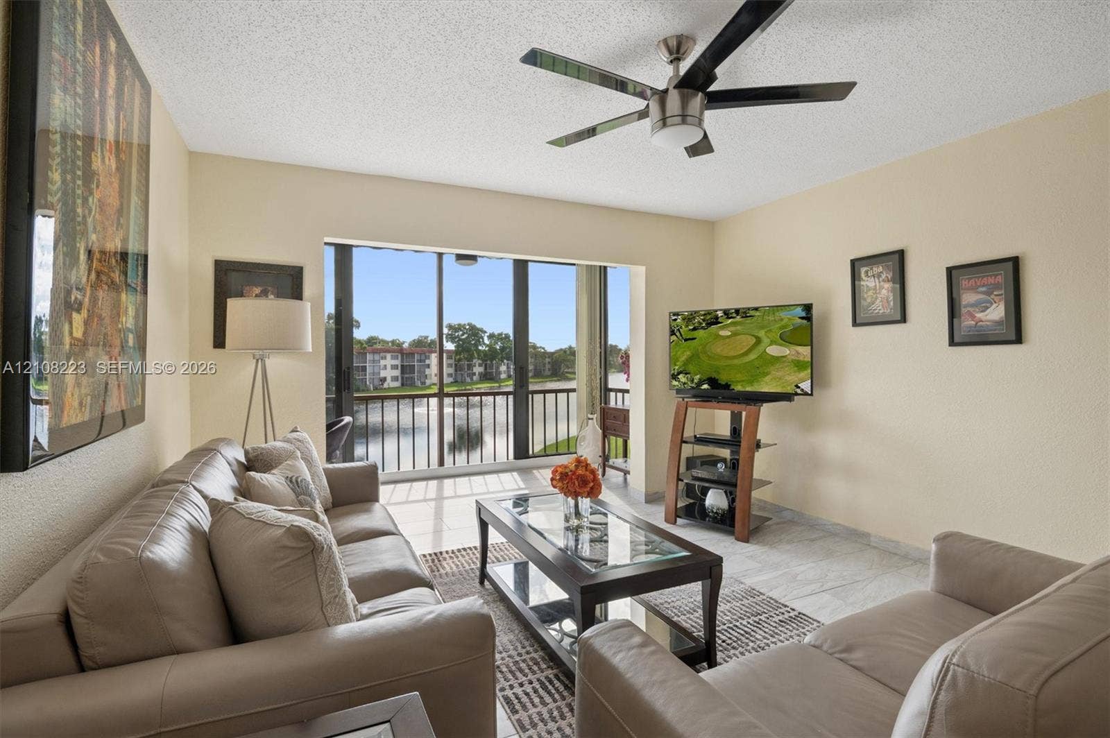 311 S Hollybrook Drive, #309, Pembroke Pines, FL 33025 Living area featuring large format tile flooring, a multi-blade ceiling fan, and floor-to-ceiling glass sliding doors opening to a railed balcony