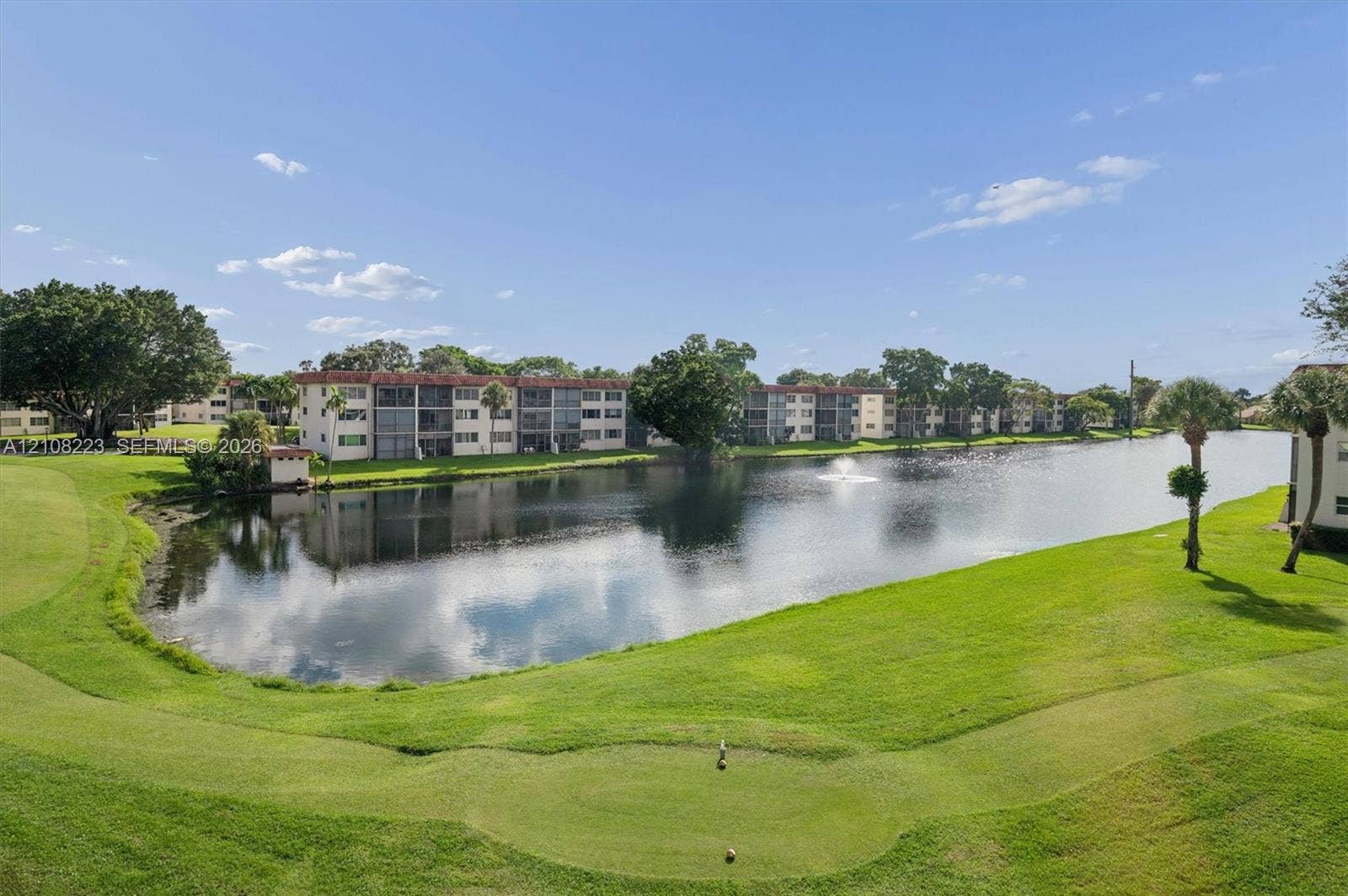 311 S Hollybrook Drive, #309, Pembroke Pines, FL 33025 Waterfront landscape featuring a pond, fountain, manicured lawn, mature trees, and palm trees