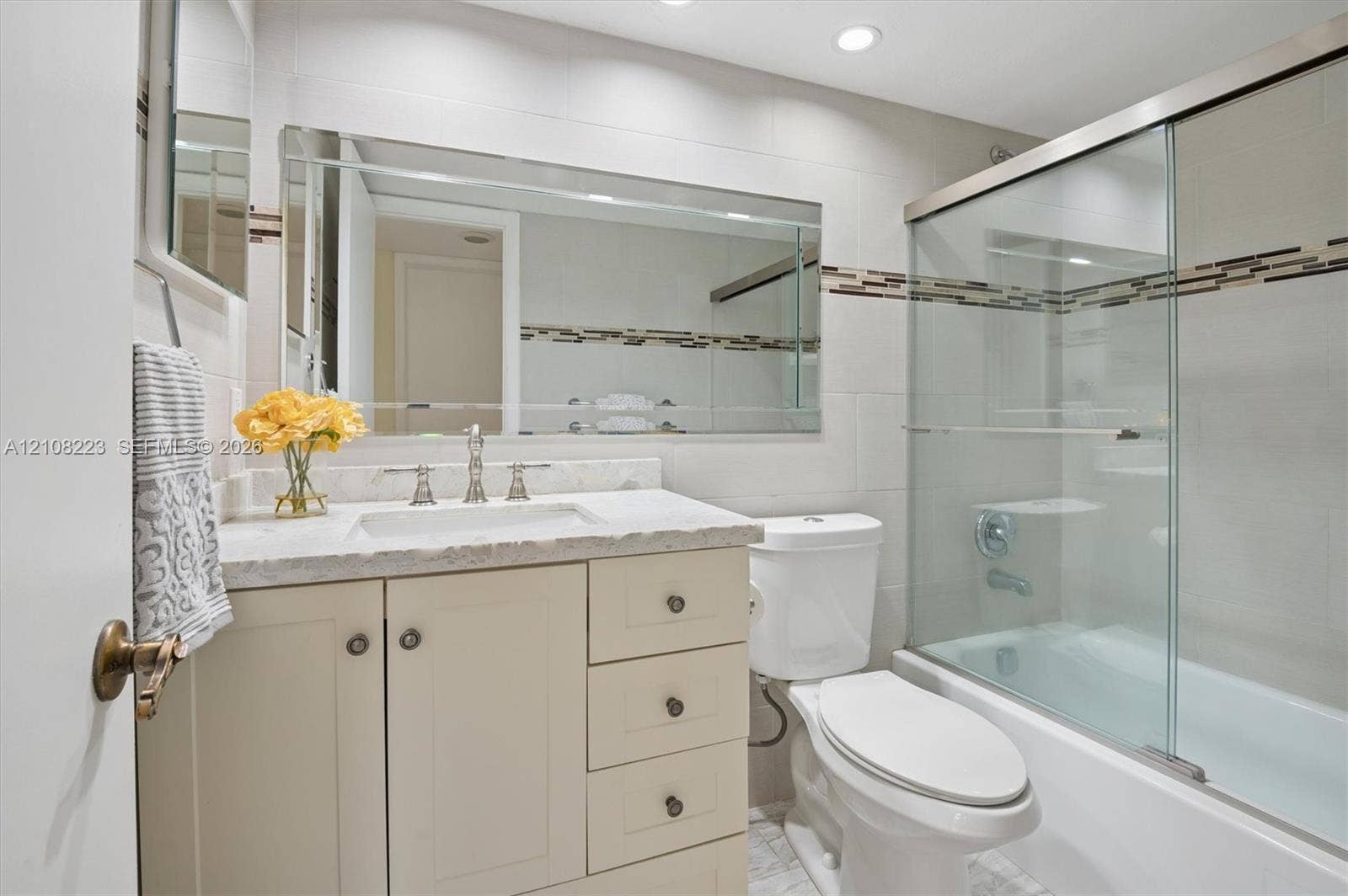 311 S Hollybrook Drive, #309, Pembroke Pines, FL 33025 Bathroom featuring a vanity with stone-finish countertop, undermount sink, recessed lighting, and a bathtub with glass sliding doors and decorative tile inlay