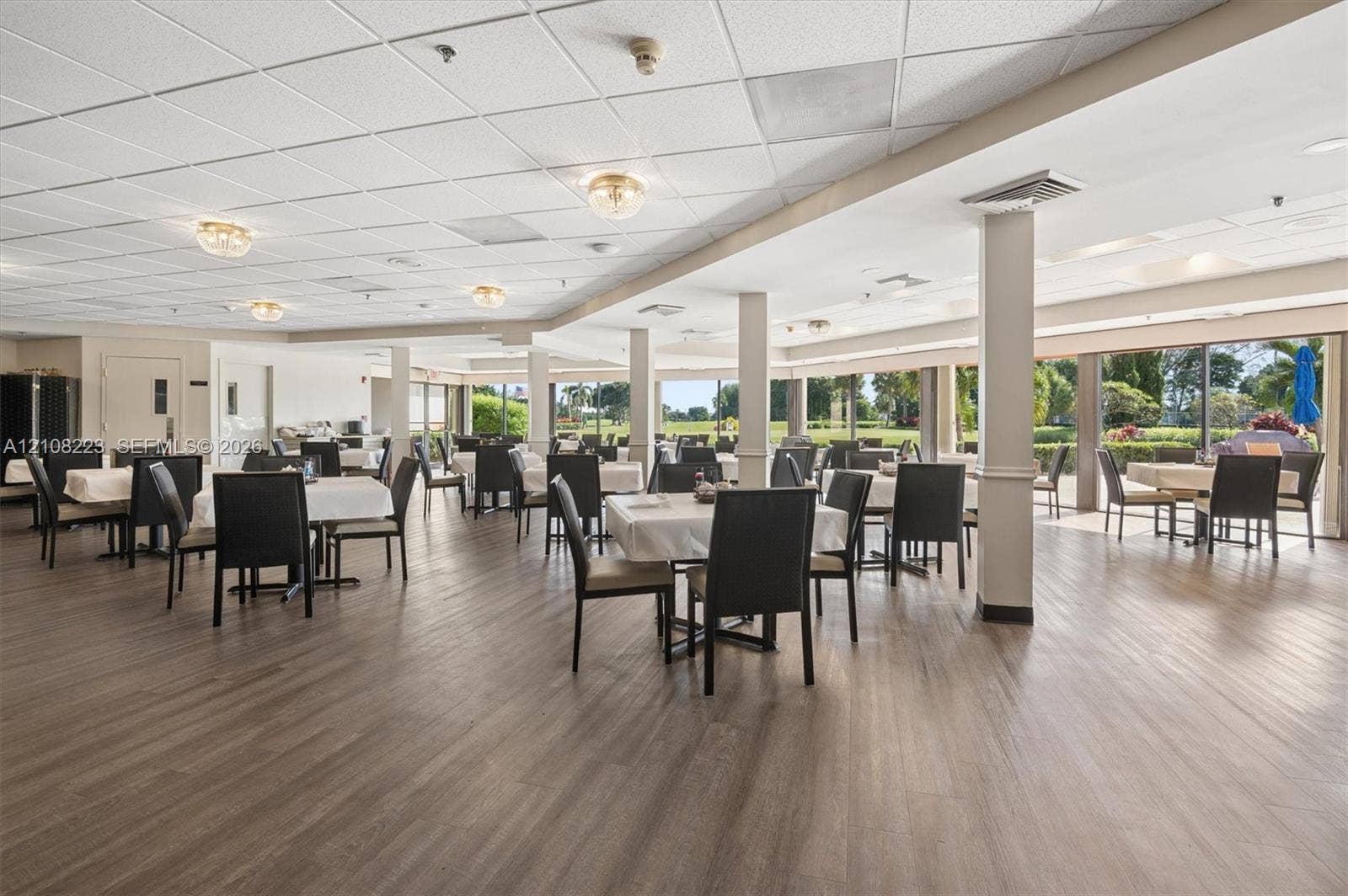 311 S Hollybrook Drive, #309, Pembroke Pines, FL 33025 Open-concept interior featuring wood-finish flooring, drop ceiling panels, structural support columns, and large-format glass sliding doors