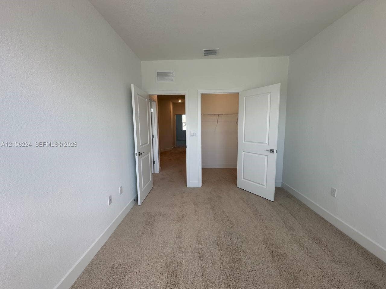 17183 SW 2nd Circle, #17183, Pembroke Pines, Pembroke Pines, FL 33027 Room featuring neutral-toned carpeting, two interior doorways with paneled doors, and a reach-in closet with integrated wire shelving