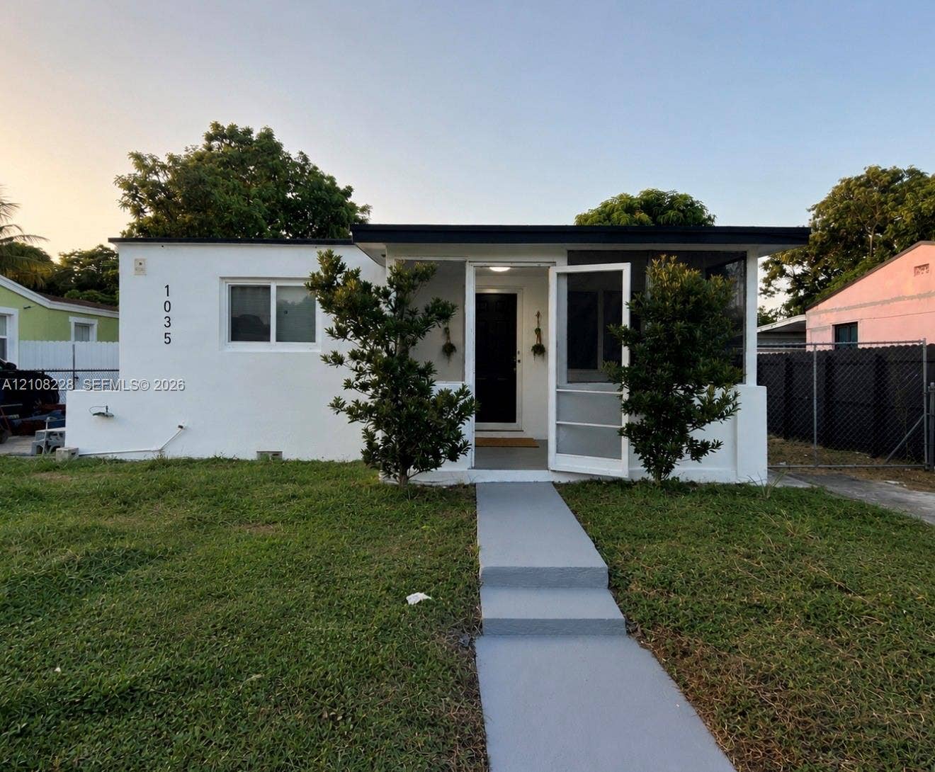 Stucco exterior with a flat roofline, covered front entryway, screen door, and paved pedestrian walkway