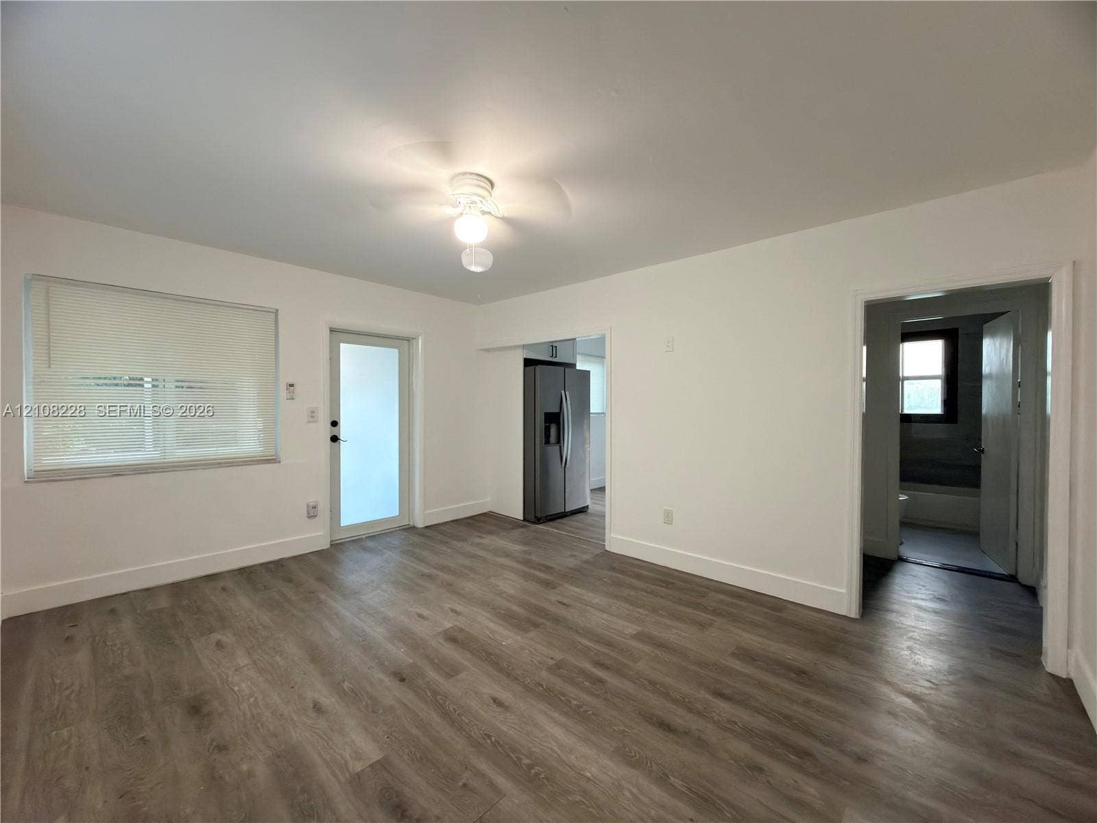 Interior space featuring wood-finish flooring, a neutral color palette, a ceiling-mounted light fixture, and an exterior door with glass paneling