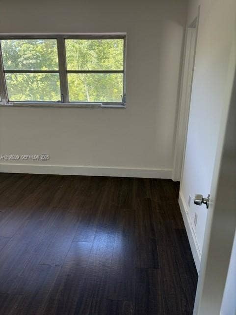 3200 Coral Springs Drive, Coral Springs, FL 33065 Room interior featuring dark wood-finish flooring, neutral wall tones, and a multi-pane horizontal window