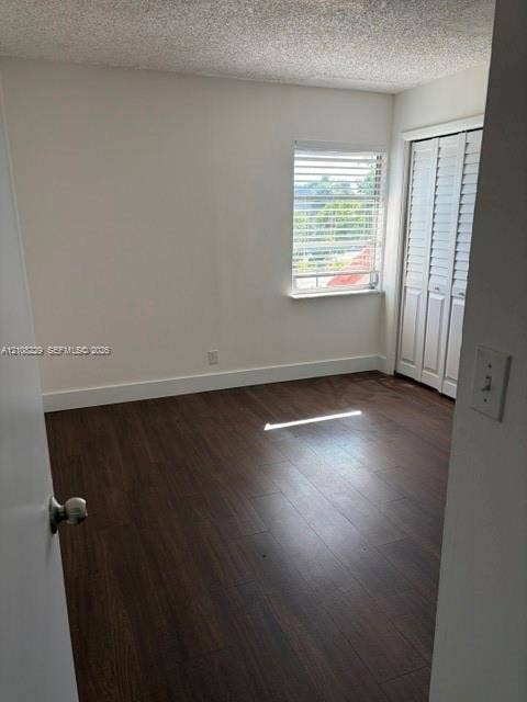 3200 Coral Springs Drive, Coral Springs, FL 33065 Room featuring wood-finish flooring, white walls, and a window with horizontal blinds, complemented by white bi-fold closet doors