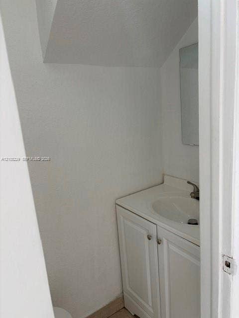 3200 Coral Springs Drive, Coral Springs, FL 33065 Vanity cabinet with white raised-panel doors, integrated sink countertop, single-handle faucet, and wall-mounted mirror