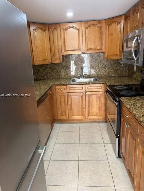 3200 Coral Springs Drive, Coral Springs, FL 33065 Kitchen featuring wood cabinetry, stone-finish countertops, stainless steel appliances, a double-basin undermount sink, and tile flooring
