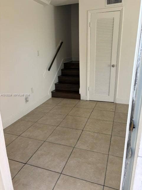 3200 Coral Springs Drive, Coral Springs, FL 33065 Neutral-toned tile flooring, dark wood-finish staircase, and louvered-panel closet door