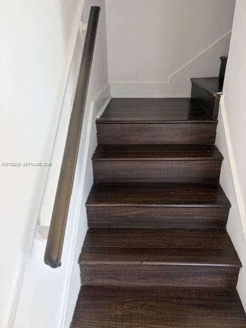 3200 Coral Springs Drive, Coral Springs, FL 33065 Staircase featuring dark-toned wood-finish treads and a coordinating round handrail