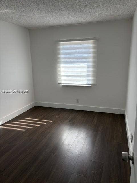 3200 Coral Springs Drive, Coral Springs, FL 33065 Neutral-toned room featuring dark wood-finish flooring, a single-pane window with zebra-style roller shades, and a textured ceiling finish