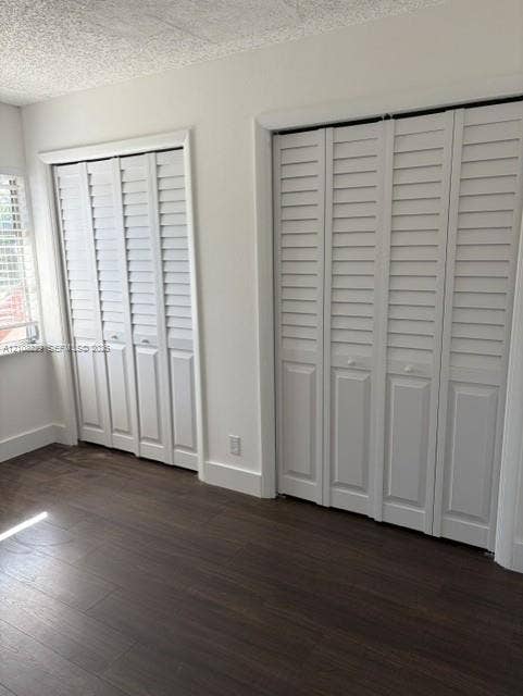 3200 Coral Springs Drive, Coral Springs, FL 33065 Two built-in bi-fold closets featuring white louvered doors, dark wood-finish flooring, and white window shutters