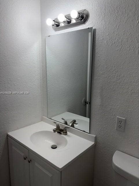 3200 Coral Springs Drive, Coral Springs, FL 33065 Bathroom vanity featuring a solid-surface countertop with an integrated basin, white cabinetry, polished metal faucet, wall-mounted mirror, and a three-light fixture
