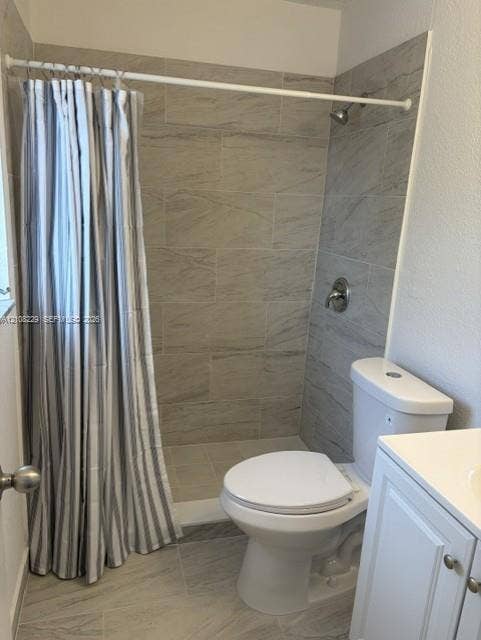 3200 Coral Springs Drive, Coral Springs, FL 33065 Full-height ceramic tile shower surround, porcelain floor tile, white vanity cabinet, dual-flush toilet, and wall-mounted shower fixture