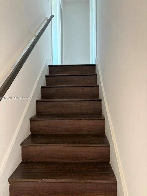 3200 Coral Springs Drive, Coral Springs, FL 33065 Staircase featuring wood-finish treads and a dark-toned handrail