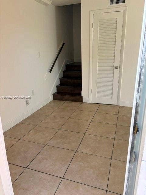 3200 Coral Springs Drive, Coral Springs, FL 33065 Neutral tile flooring, wood-finish staircase treads, and a classic louvered closet door