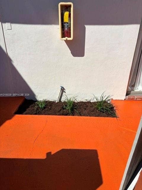 3200 Coral Springs Drive, Coral Springs, FL 33065 Painted concrete patio featuring a rectangular garden bed with planted greenery and an exterior wall-mounted fire extinguisher cabinet