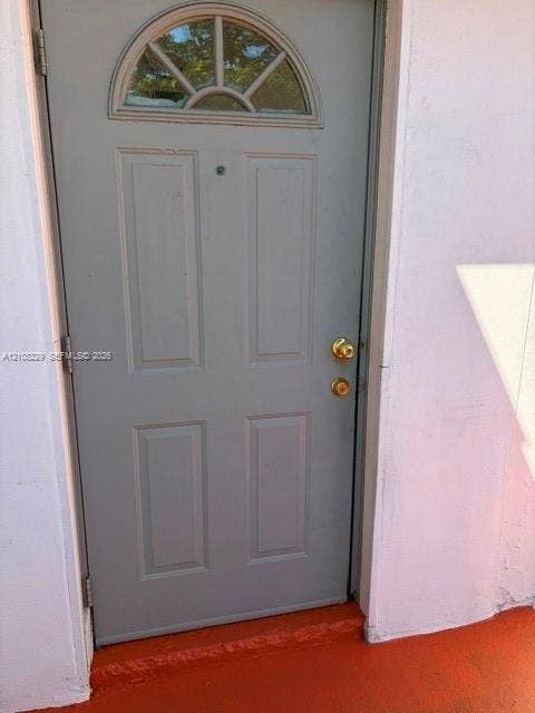 3200 Coral Springs Drive, Coral Springs, FL 33065 Gray four-panel door featuring a semi-circular transom window, brass-finish hardware, and a door viewer
