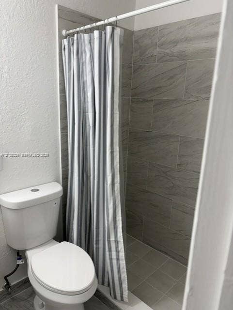 3200 Coral Springs Drive, Coral Springs, FL 33065 Shower enclosure featuring floor-to-ceiling large-format neutral-toned tile work and a white porcelain commode