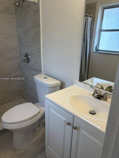 3200 Coral Springs Drive, Coral Springs, FL 33065 Bathroom featuring a vanity with a white countertop and oval under-mount sink, tile shower surround, and neutral floor tiling