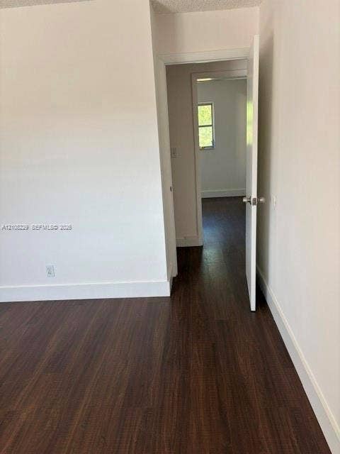 3200 Coral Springs Drive, Coral Springs, FL 33065 Interior room featuring white-painted walls and dark wood-finish flooring