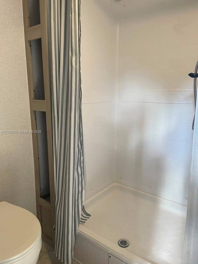 573 Mokena Drive, #1, Miami Springs, Miami Springs, FL 33166 Shower stall featuring a molded composite surround, integrated shelving unit, and handheld shower fixture