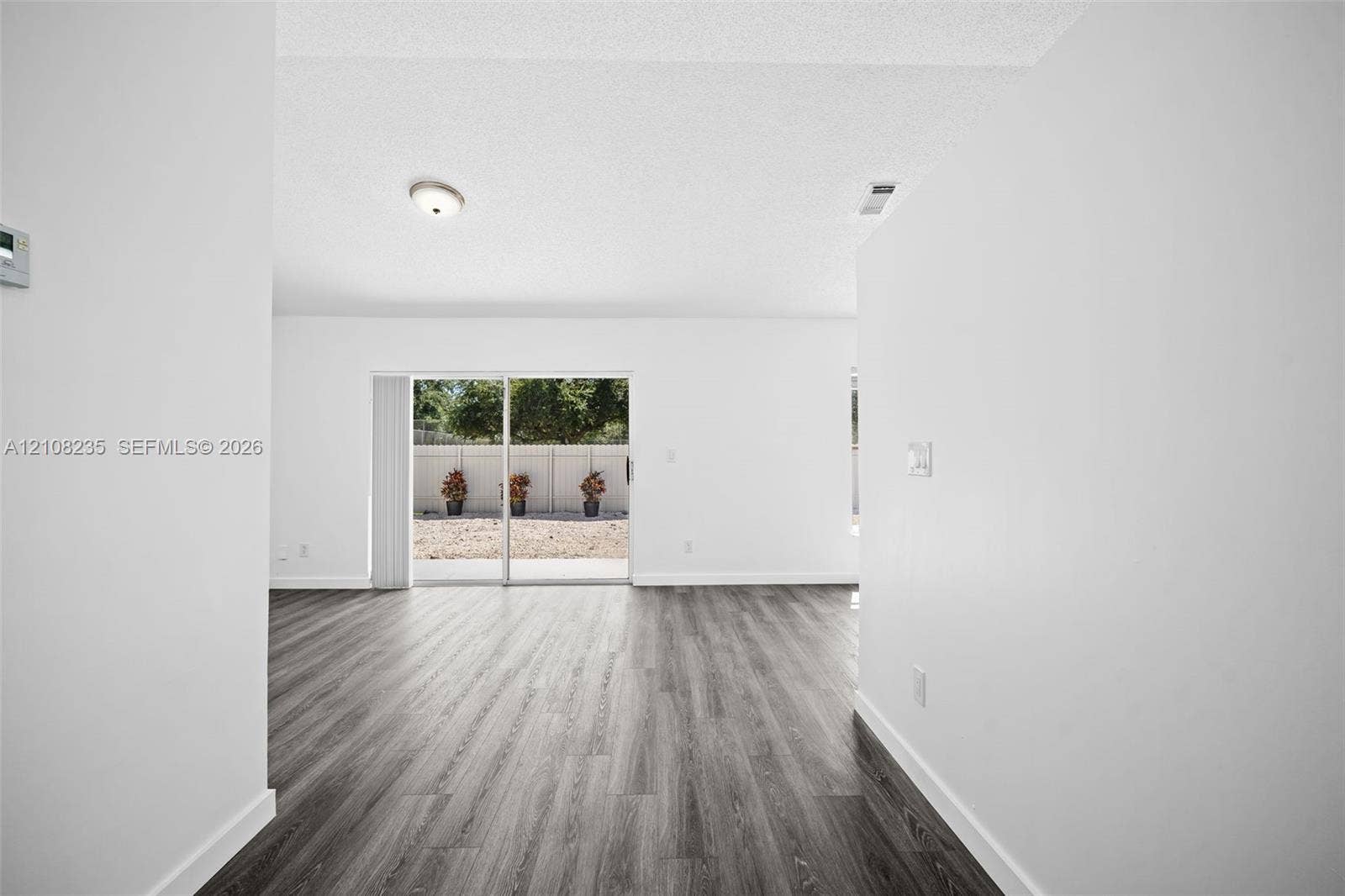 12752 SW 250th Terrace, Homestead, FL 33032 Wood-finish flooring, white walls, and glass sliding door providing exterior access to a fenced rear area