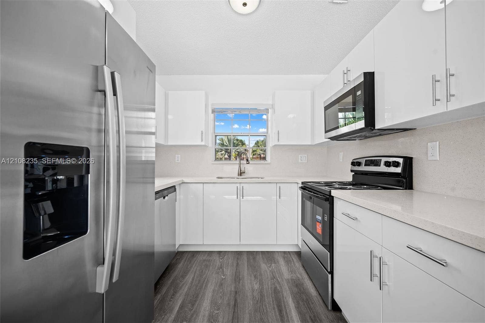 12752 SW 250th Terrace, Homestead, FL 33032 Kitchen featuring high-gloss white cabinetry, light-toned stone countertops, stainless steel appliances, and wood-finish flooring