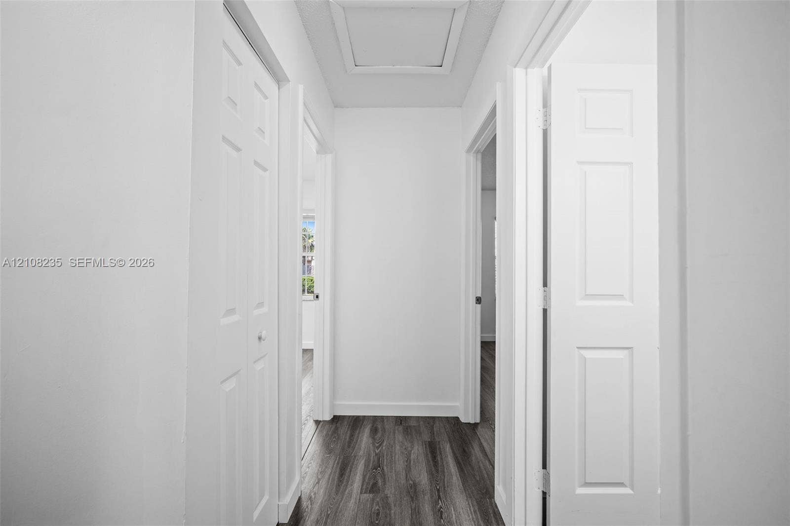 12752 SW 250th Terrace, Homestead, FL 33032 Hallway featuring wood-finish flooring, six-panel interior doors, and a ceiling access panel
