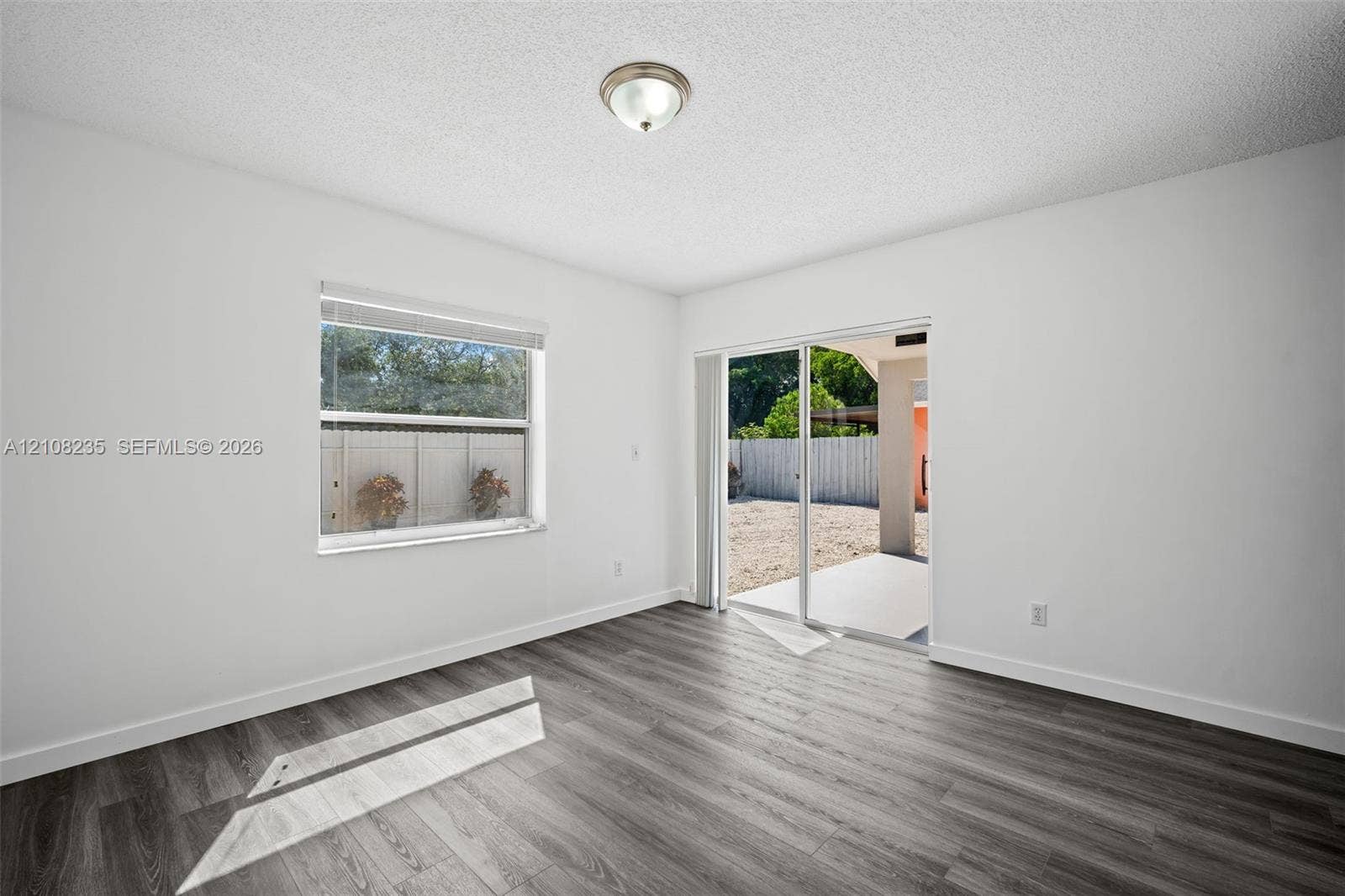 12752 SW 250th Terrace, Homestead, FL 33032 Interior space featuring wood-finish flooring, sliding glass door, single-pane window, and a central ceiling-mounted light fixture
