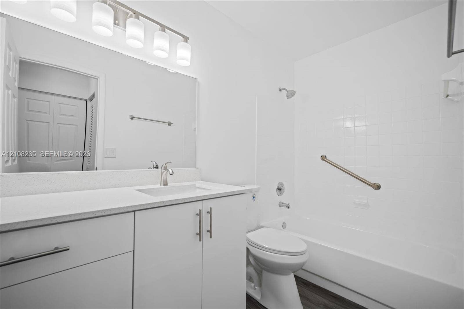 12752 SW 250th Terrace, Homestead, FL 33032 Bathroom featuring a white vanity with a solid surface countertop, an integrated sink, a full-width mirror, five-light overhead fixture, and a tile-surround shower and tub combination