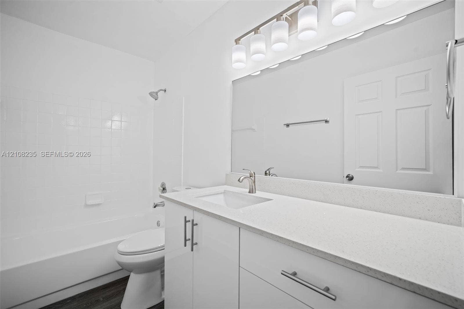 12752 SW 250th Terrace, Homestead, FL 33032 Bathroom featuring a white vanity cabinet, solid surface countertop with an integrated basin, full-width vanity mirror, five-light fixture, and a tub-shower combination with tile surround
